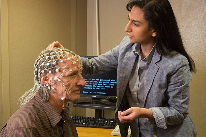 研究人员帮助一名志愿者进入脑电图设备