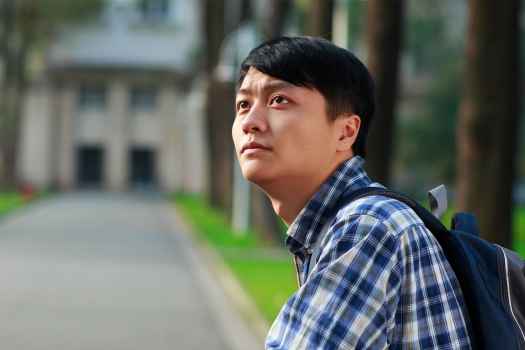 亚洲男人背包和格子衬衫抬头。