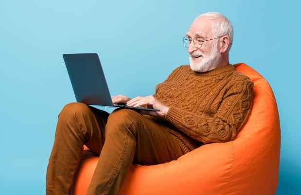 老人坐在豆袋椅上看着笔记本电脑